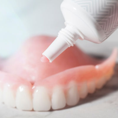 Dentures with adhesive